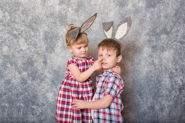 Dos niños, una niña y un niño con orejas de conejo de Pascua en la cabeza, se ríen y juegan Espacio de copia de Pascua familiar