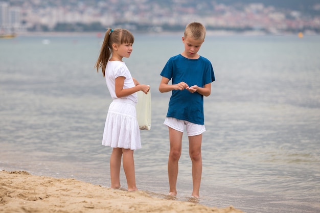 Dos niños niño y niña caminando descalzo sobre el agua de la orilla del mar en verano.