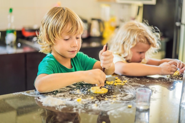 Dos niños, un niño y una niña, hacen galletas con masa.