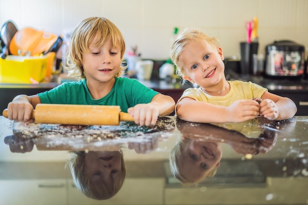 Dos niños, un niño y una niña, hacen galletas con masa.