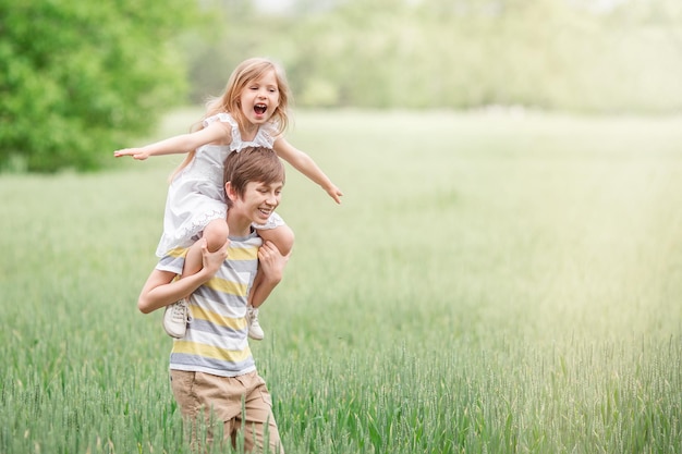 Dos niños, un niño y una niña juntos al aire libre fuera de hermano y hermana juegan en un campo
