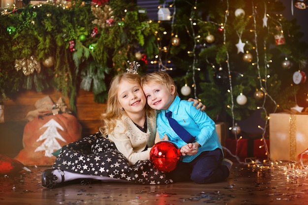 dos niños pequeños cerca con un árbol de navidad