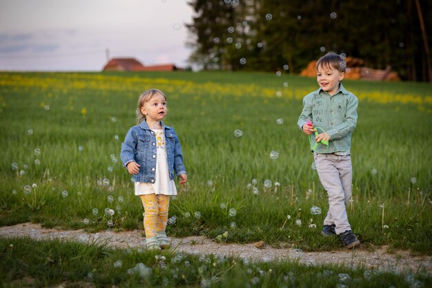 Dos niños pequeños corriendo en un campo verde entre flores.