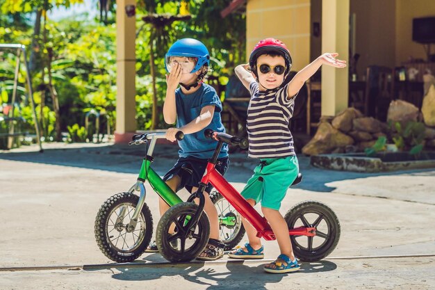 Dos niños pequeños divirtiéndose en bicicleta de equilibrio en una carretera tropical del país