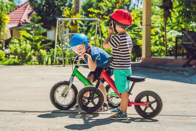 Dos niños pequeños divirtiéndose en bicicleta de equilibrio en una carretera tropical del país