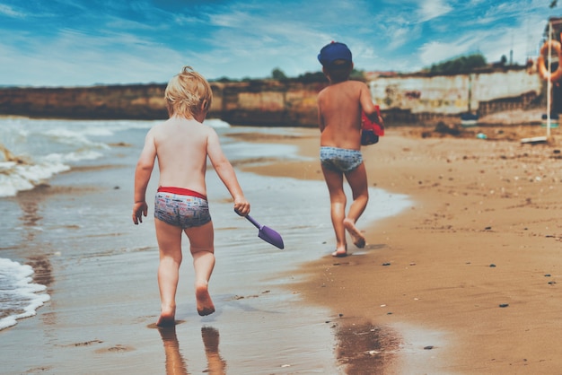 Dos niños pequeños están jugando en la orilla del mar.