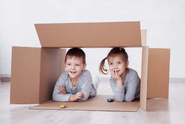 Dos niños pequeños niño y niña jugando autos pequeños en cajas de cartón. Foto de concepto. Los niños se divierten. Foto de concepto. Los niños se divierten