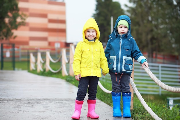 Dos niños pequeños, un niño y una niña, ven un espectáculo de monos en el zoológico en un frío día de otoño