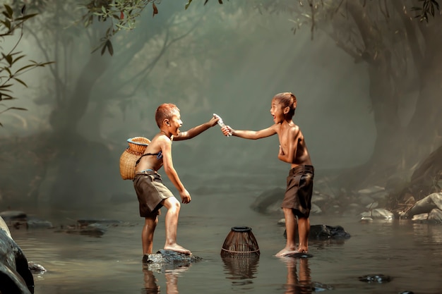 Dos niños pescando en un arroyo cerca de la casa en las zonas rurales de Tailandia