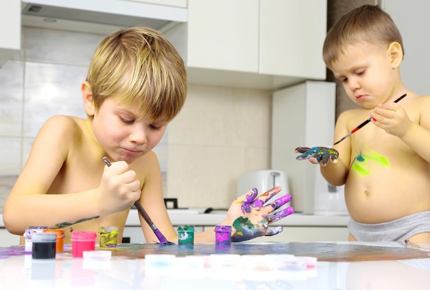 Dos niños pintan sobre una mesa blanca. creatividad artística en el desarrollo infantil