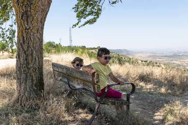 Dos niños sentados en un cenador de campo mirando la naturaleza