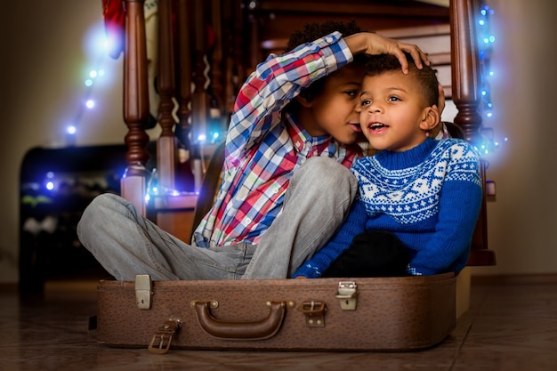 Dos niños sentados y susurrando. Niños afro susurrando y sonriendo. Ahora conoces el secreto. Déjame decirte algo.