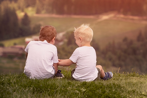 Dos niños se sientan en la colina y hablan alegremente