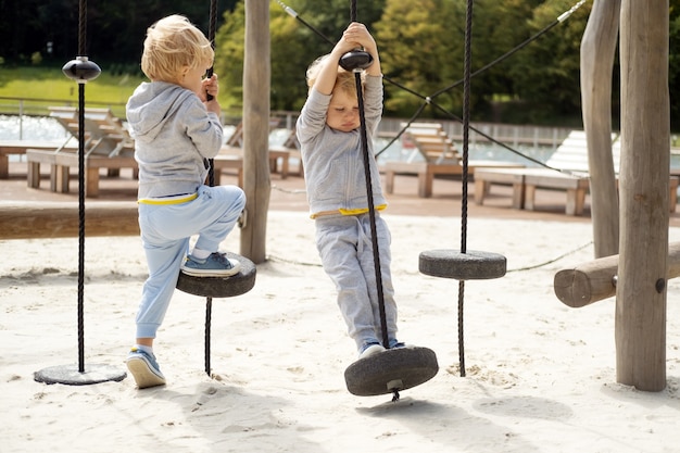 Dos niños varones hermanos gemelos jugando en un parque infantil en un soleado día de otoño.