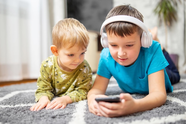 Dos niños viendo teléfonos inteligentes niños felices usando teléfonos inteligentes juntos