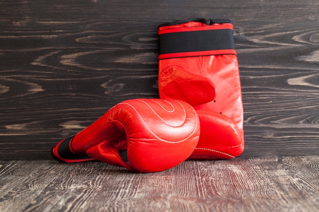 Dos nuevos guantes de boxeo rojos sobre un fondo de madera negra