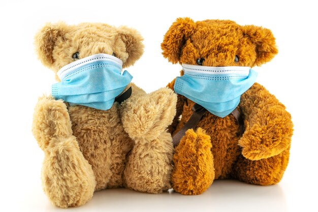 Dos osos de peluche con máscara protectora, el oso de peluche está sentado con máscaras médicas azules sobre fondo blanco, el concepto de protección contra las enfermedades respiratorias, el concepto de detener el coronavirus y la contaminación del aire.