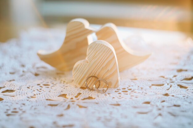 Dos pájaros de juguete hechos a mano de madera con dos anillos de bodas dorados y corazón Propuesta de amor de boda matrimonio concepto de familia