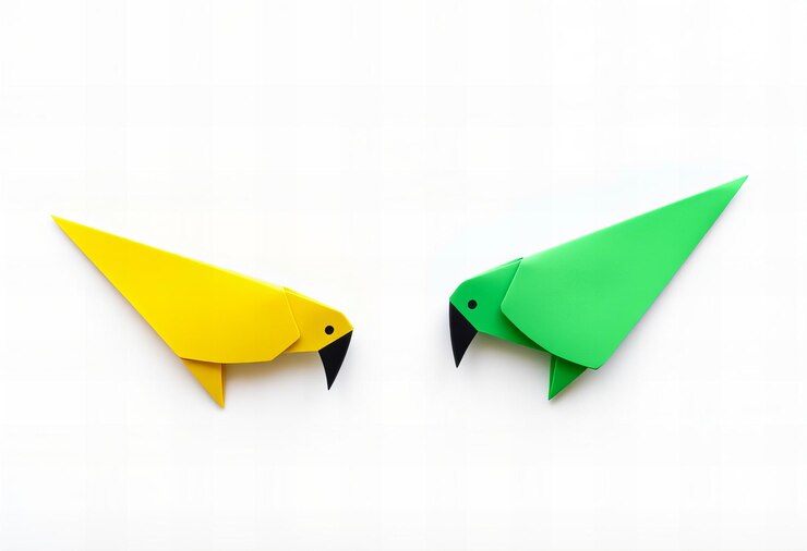 Foto dos pájaros de papel amarillo y verde están en una superficie blanca