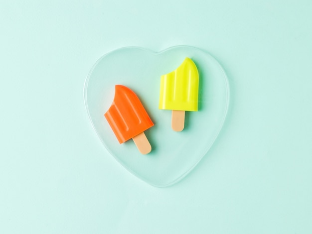 Dos paletas de hielo mordidas en un corazón de cristal sobre un fondo azul. Un bocadillo popular de verano.