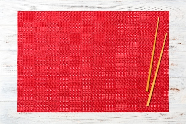 Dos palillos de sushi con mantel rojo vacío, servilleta sobre superficie de madera blanca Vista superior con espacio de copia
