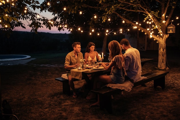 Dos parejas disfrutando de una cena en el jardín.