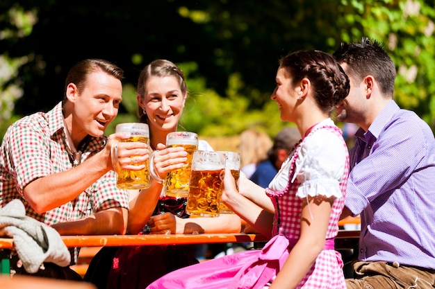 Dos parejas felices sentados en el jardín de la cerveza