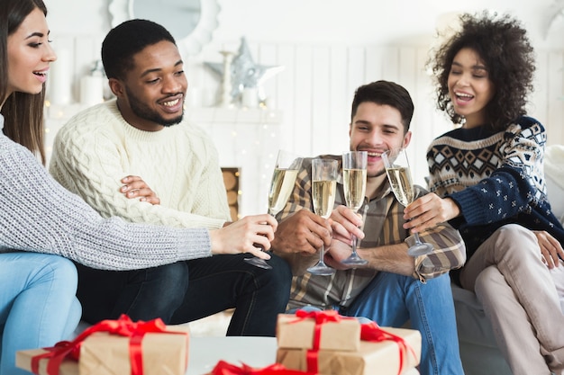 Dos parejas jóvenes celebrando el año nuevo y brindando con champán en casa