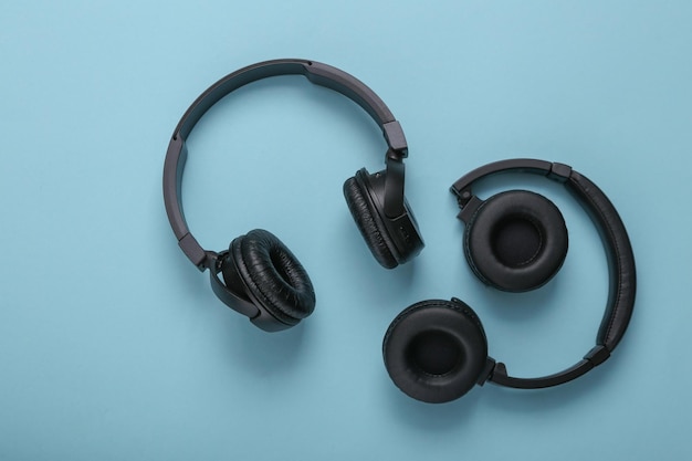 Dos pares de auriculares estéreo inalámbricos negros sobre un fondo azul.