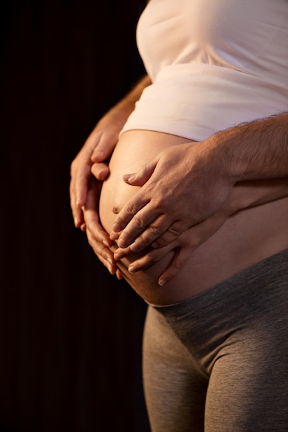 Dos pares de manos en el vientre de la mujer embarazada.