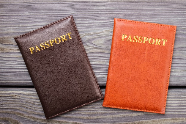 Dos pasaportes en madera. Pasaporte marrón y rojo sobre el escritorio.