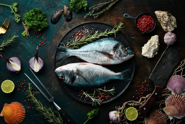 Dos peces dorados con especias en un plato de piedra negra Sobre un fondo oscuro Vista superior