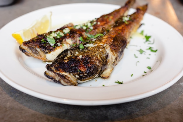 Foto dos peces gobio de mar frito en un plato blanco con limón closeup