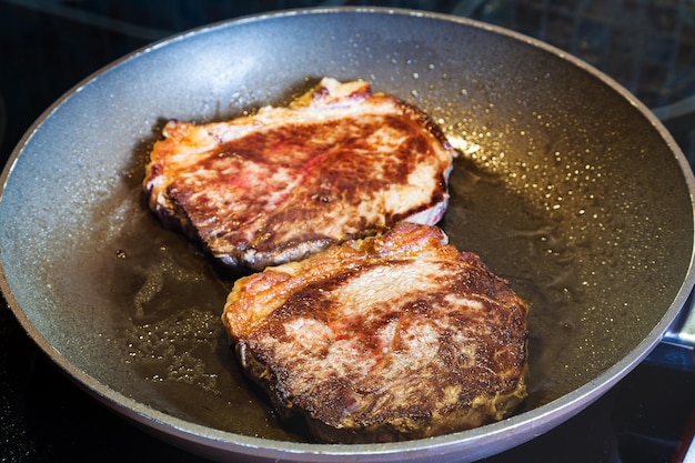 Dos pedazos de carne asada en una sartén en el rango