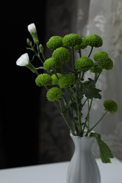 Dos pequeñas rosas blancas adornan un ramo de crisantemos verdes