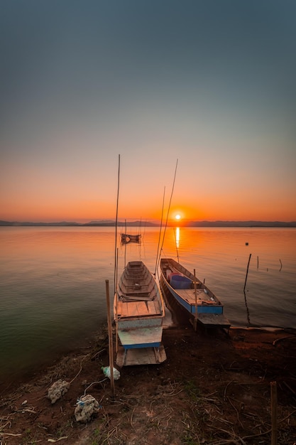 Foto dos pequeños botes amarrados en la orilla del lago. al atardecer