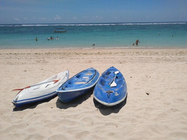 Dos pequeños botes en la playa con el océano al fondo.