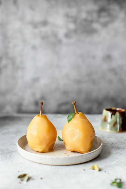 Dos peras escalfadas guisadas en almíbar picante. delicioso y saludable postre de frutas. Textura de mesa gris. copia espacio