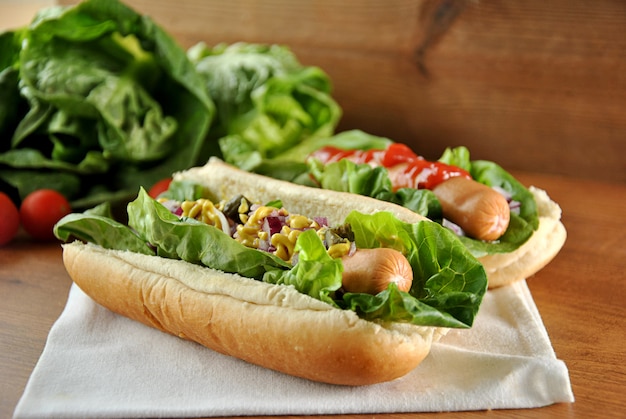 Dos perros calientes con ensalada, cebolla y salsa.