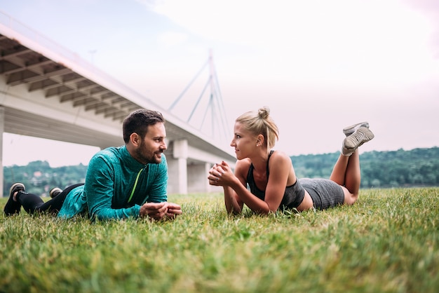 Dos personas aptas que se relajan después de hacer ejercicio al aire libre.