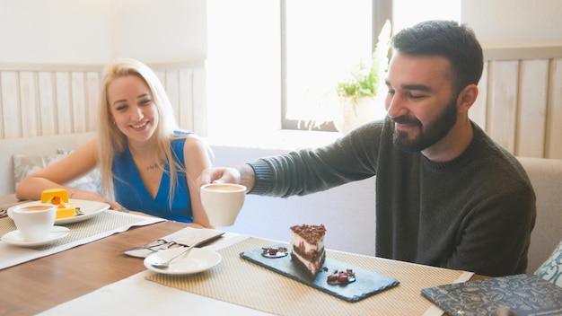 Dos personas caucásicas en el café disfrutando de los postres y hablando de cerca