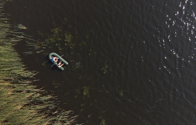 Dos personas están flotando en un bote inflable a lo largo de los matorrales de caña Vista aérea