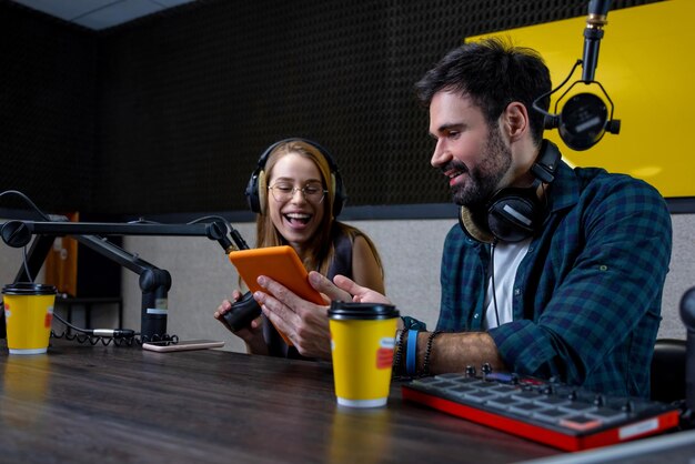 Dos personas en el estudio preparando un programa de radio.