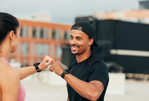 Dos personas de fitness dando golpes de puño mientras están de pie en el techo