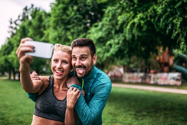 Dos personas en forma haciendo caras divertidas mientras toman selfie al aire libre.