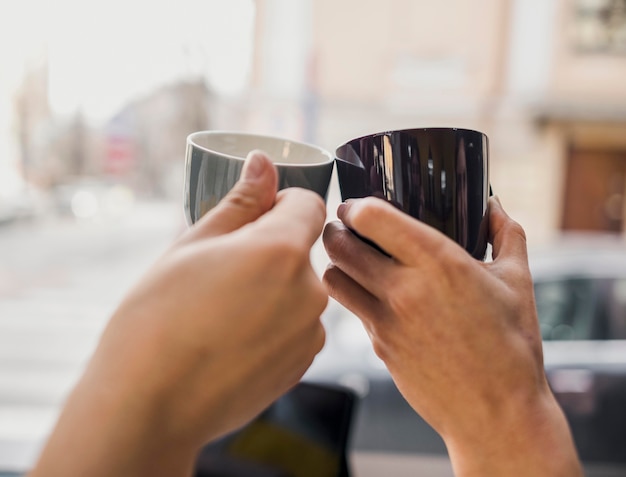 Foto dos personas golpeando tazas de café juntas