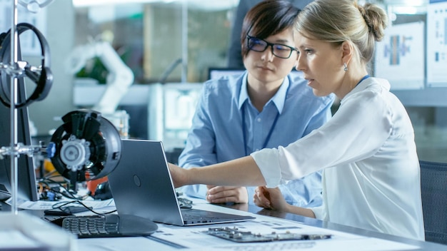 Dos personas mirando la pantalla de una computadora con un gran reloj