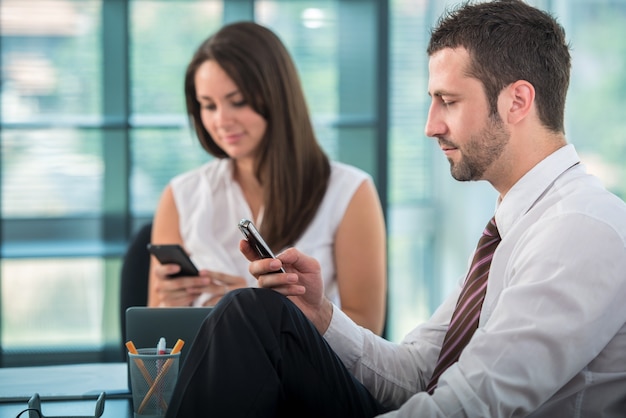 Dos personas de negocios enviando mensajes de texto