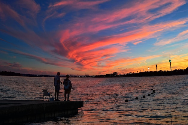 Dos personas se paran en un muelle frente a un cielo colorido con las palabras vista al lago.