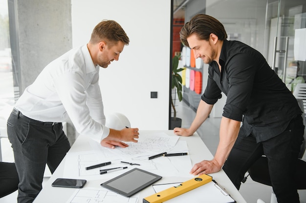 Dos personas se sientan frente al plan de construcción y hablan sobre la arquitectura.